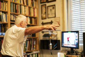 A man with Parkinson's disease sitting in front of the monitor doing his exercises.