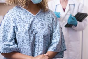 A woman standing in front of the machine about to get a mammogram.
