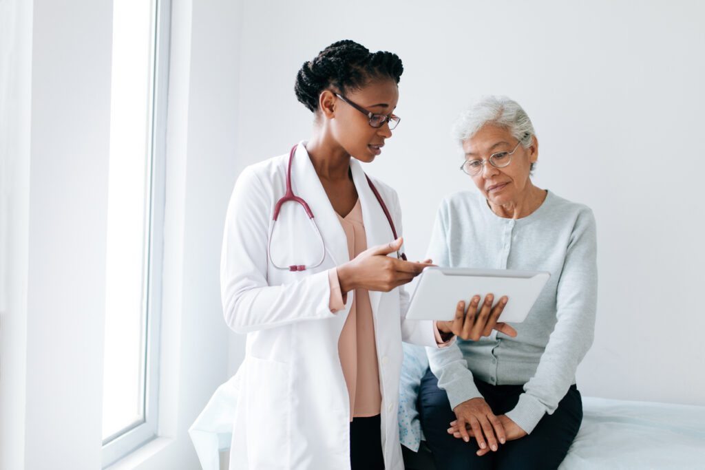 Family doctor showing digital tablet to senior patient