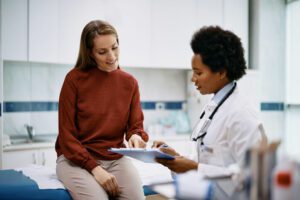 Happy woman going through her medical data with Primary care Doctor