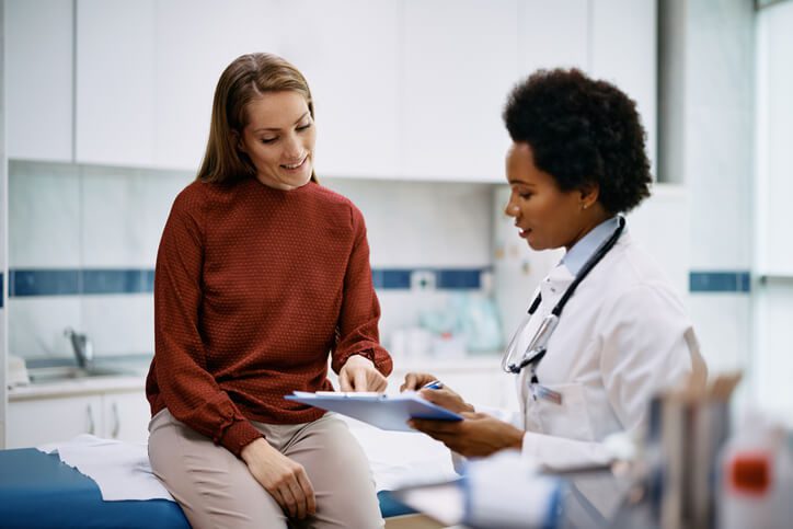 Happy woman going through her medical data with Primary care Doctor