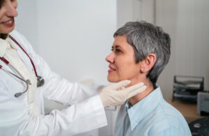endocrinologist palpating female patient thyroid gland