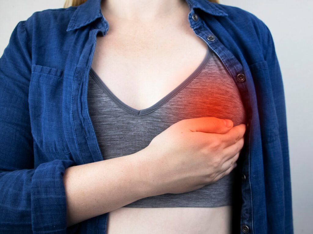 Image of a woman experiencing pain in her breast, a symptom of breast cancer.