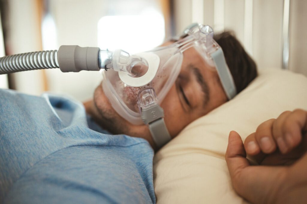 A man is sleeping with a CPAP machine for his sleep apnea.