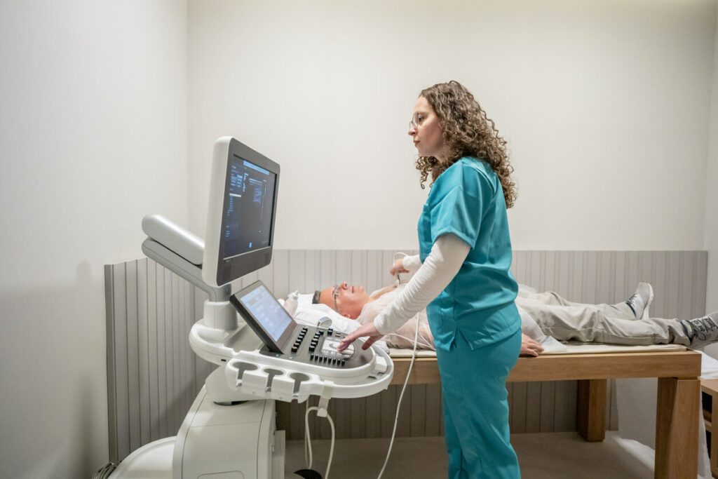 A senior man undergoing an echocardiogram during his appointment with a cardiologist.
