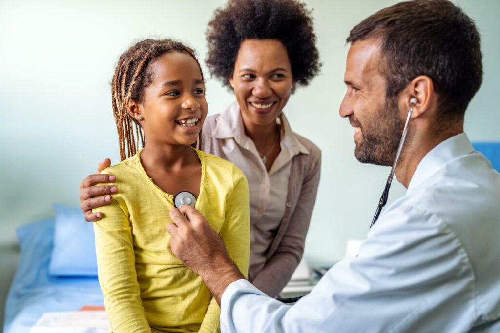 A male family doctor examines a female child patient with her mother at the family practice hospital.