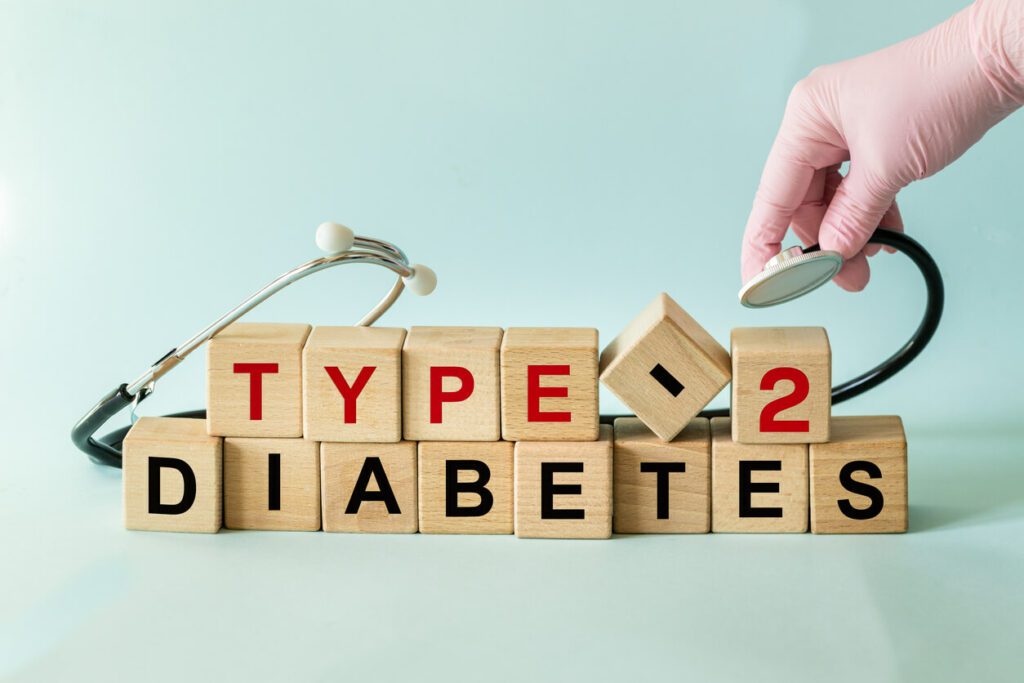 Type 2 diabetes, written on wooden blocks, with a hand holding a stethoscope.