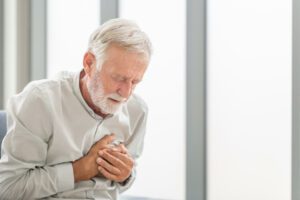A senior man places his hand on his chest as he experiences chest pain.