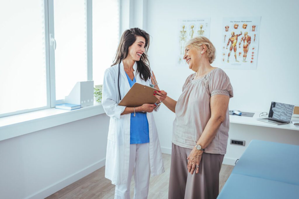 A senior woman is indoors in a hospital room for her annual wellness visit.