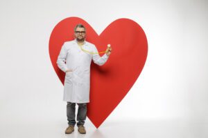 Male cardiologist (heart doctor) checking heart symbol with stethoscope for heart health awareness